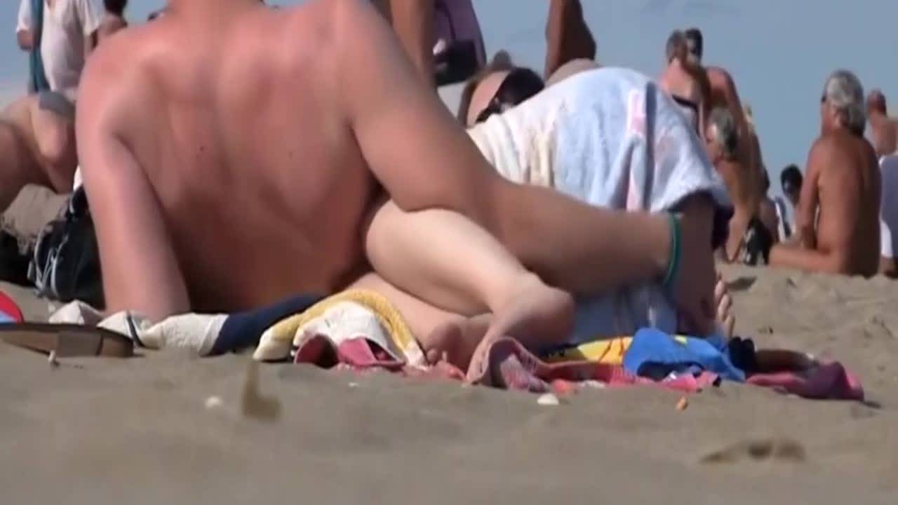 Voyeur filme un couple nudiste se caresser sur la plage